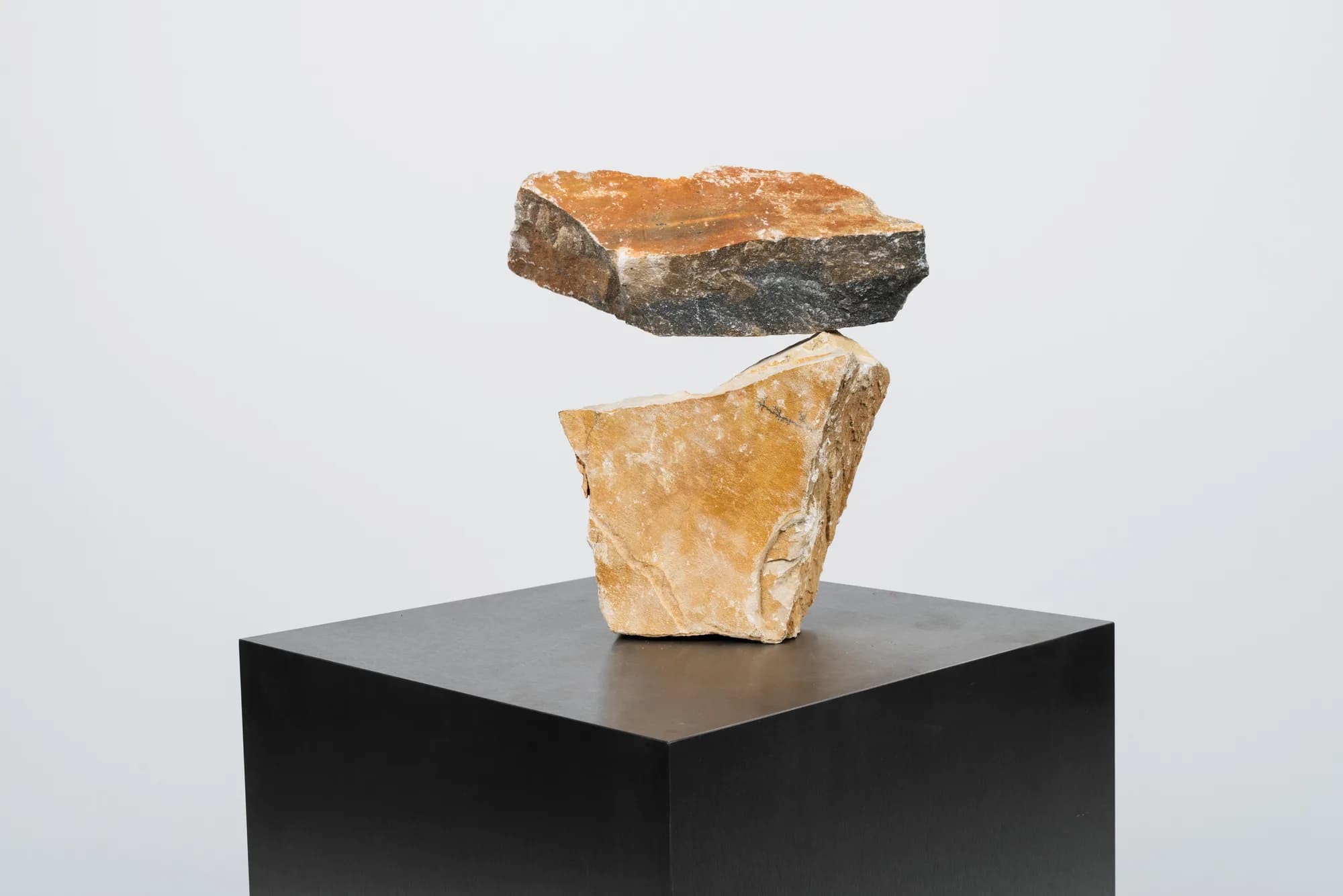 Dos piezas de piedra apiladas sobre una peana negra