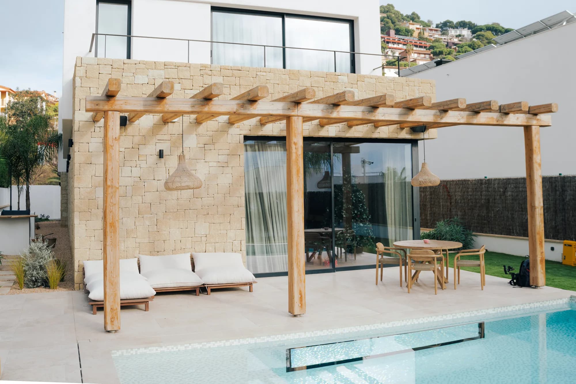 Pérgola de madera y piscina junto al muro de amarillo diamante